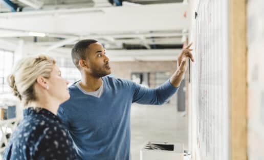 two CX consultants pointing to a whiteboard to strategize customer experience management